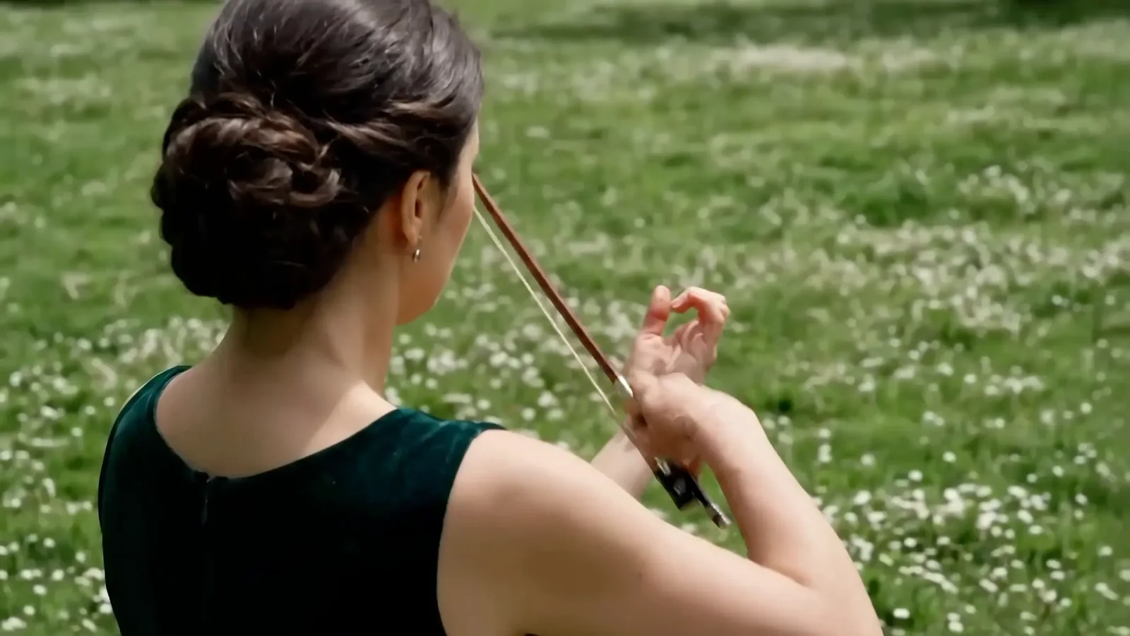 A person playing a violin outdoors, representing extended video generation capabilities.
