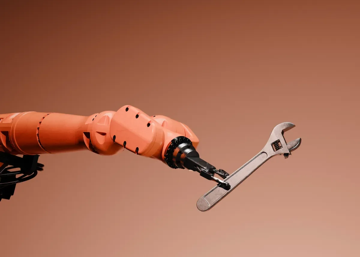 An orange robotic arm holding an adjustable wrench against a neutral background.