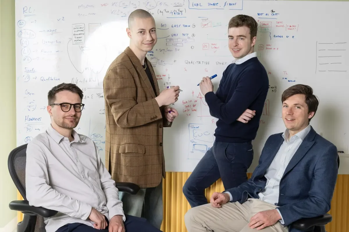 Four cofounders of Inherent posing in front of a whiteboard covered in equations and research notes.